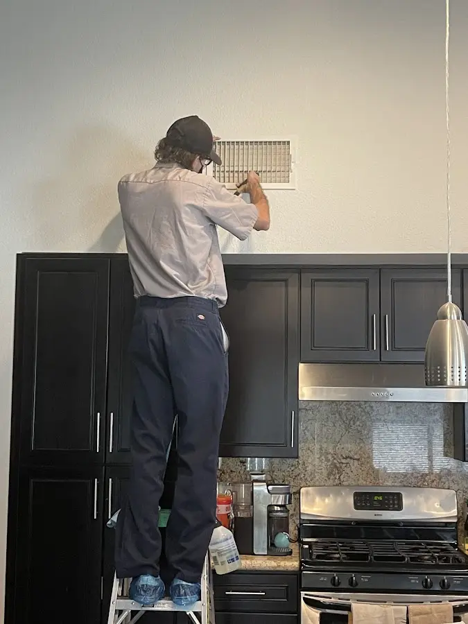 Technician inspecting an air vent during HVAC service in Dover